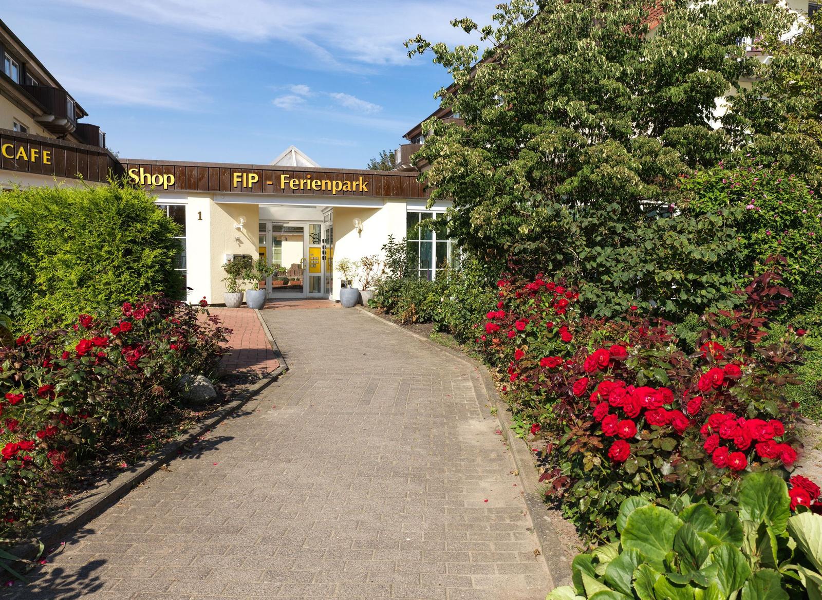 Ein Gebäude mit Balkonen und einem blühenden Garten vorne.
