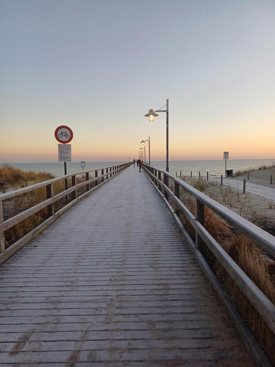 Sandweg führt zum Strand bei Sonnenuntergang mit farbigen Himmel und Wellen.