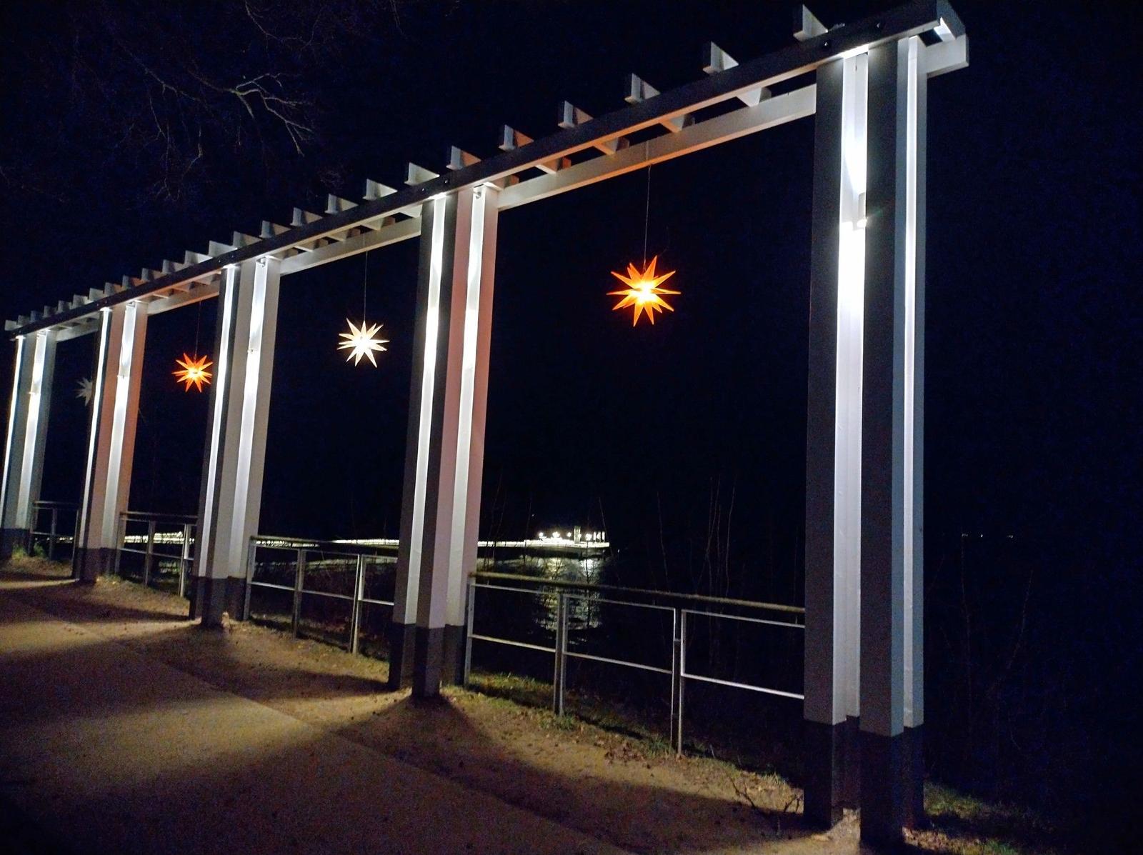 Schneebedeckter Strand mit Seeuferpromenade und kahlen Bäumen.
