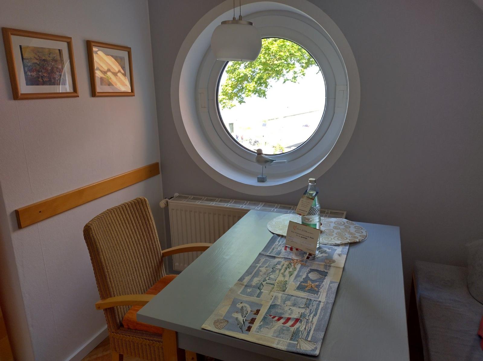 Durch runden Fensterblick auf Strand, See und Bäume