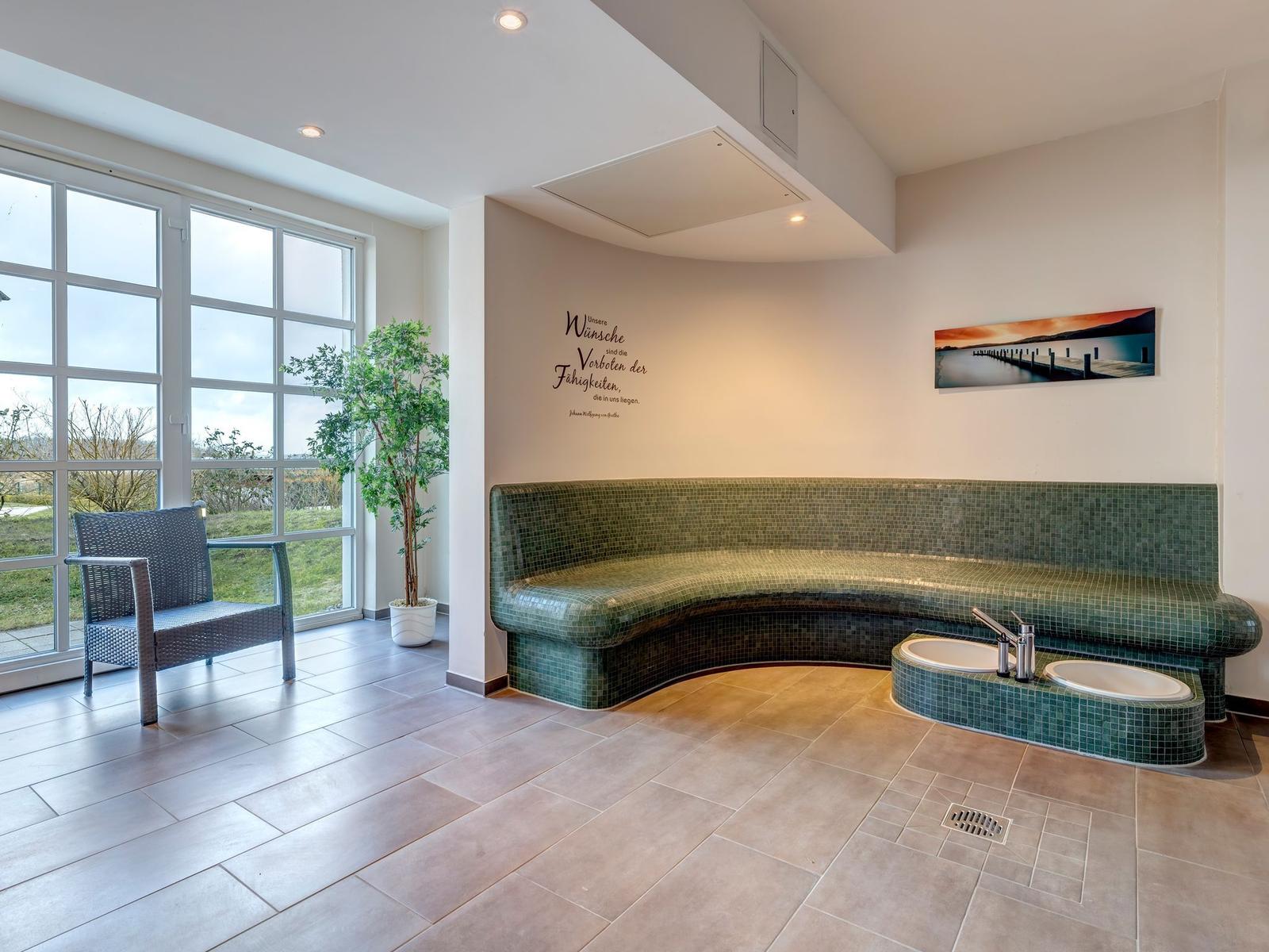 Two green lounge chairs with red blankets stand before large windows.