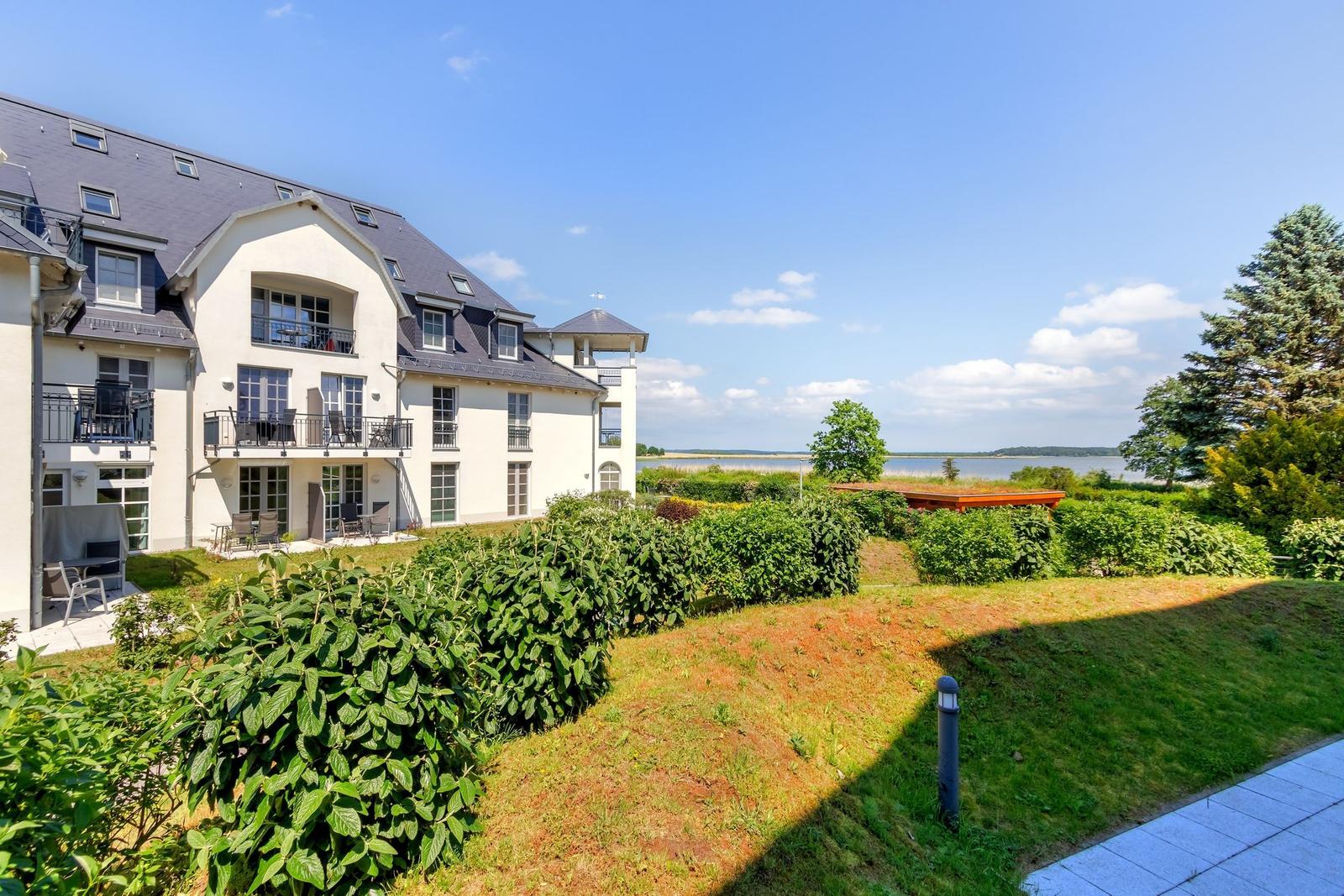 Modernes Mehrfamilienhaus mit Balkonen und Dachfenstern unter blauem Himmel.