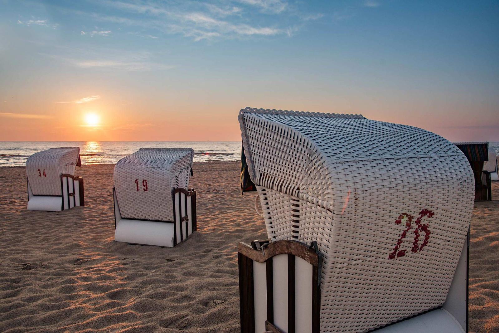 Familie springt am Strand bei Sonnenuntergang zusammengehalten.