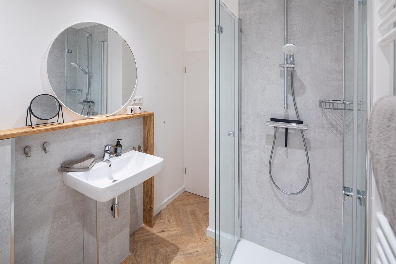 Badezimmer mit Dusche, Waschbecken und Handtuchheizung.