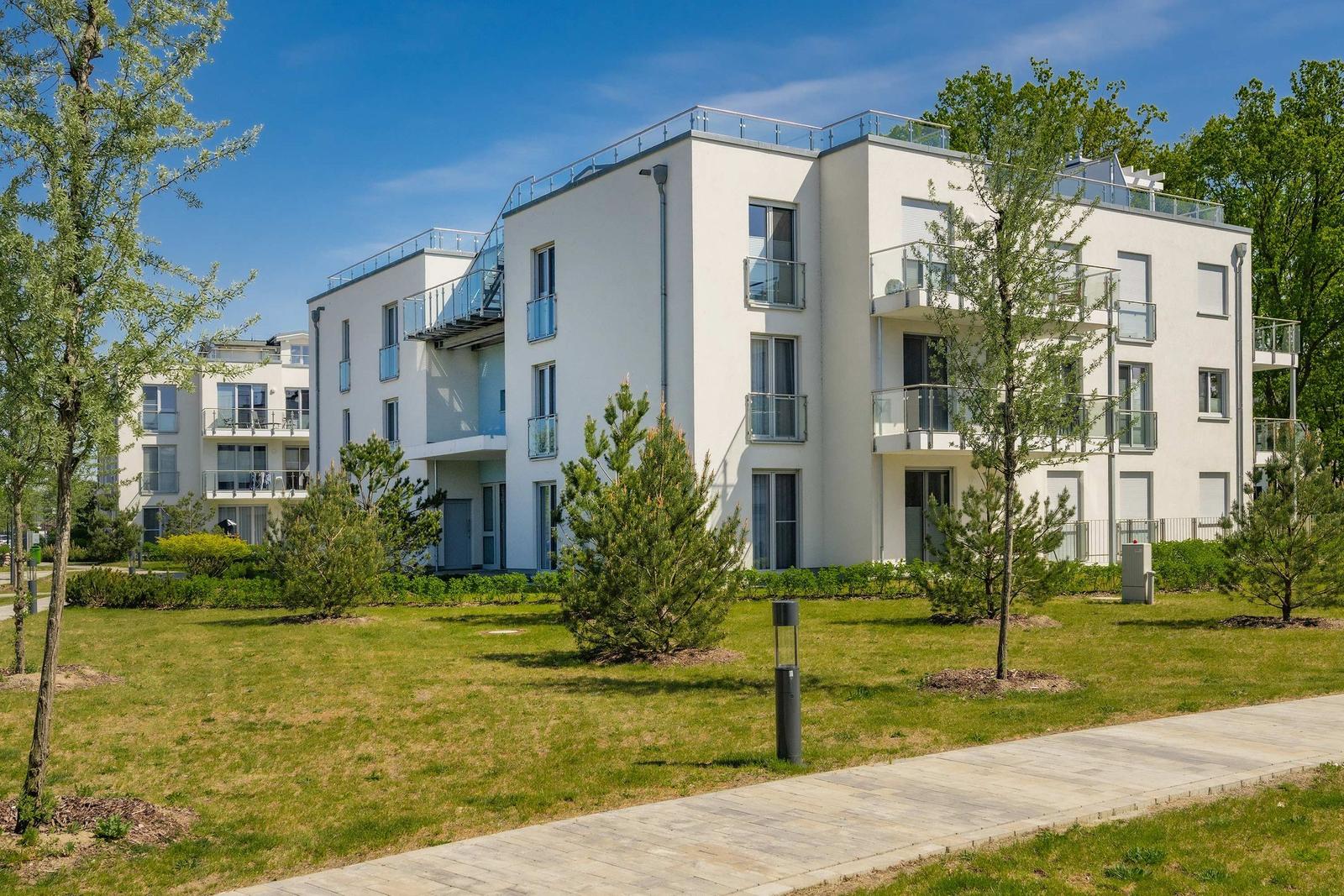Modernes Mehrfamilienhaus mit Balkonen und grünem Außenbereich.