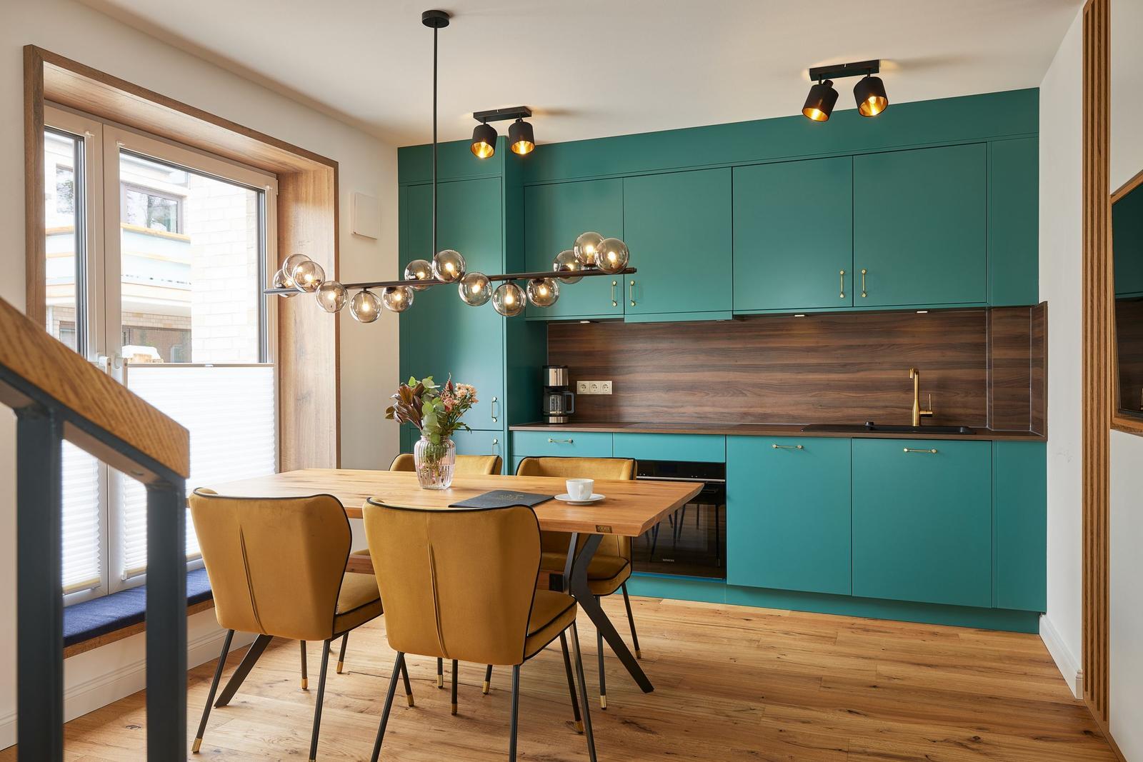 Ein Wohnzimmer mit blauem Sofa, gelben und blauen Sesseln sowie zwei runden Tischen.