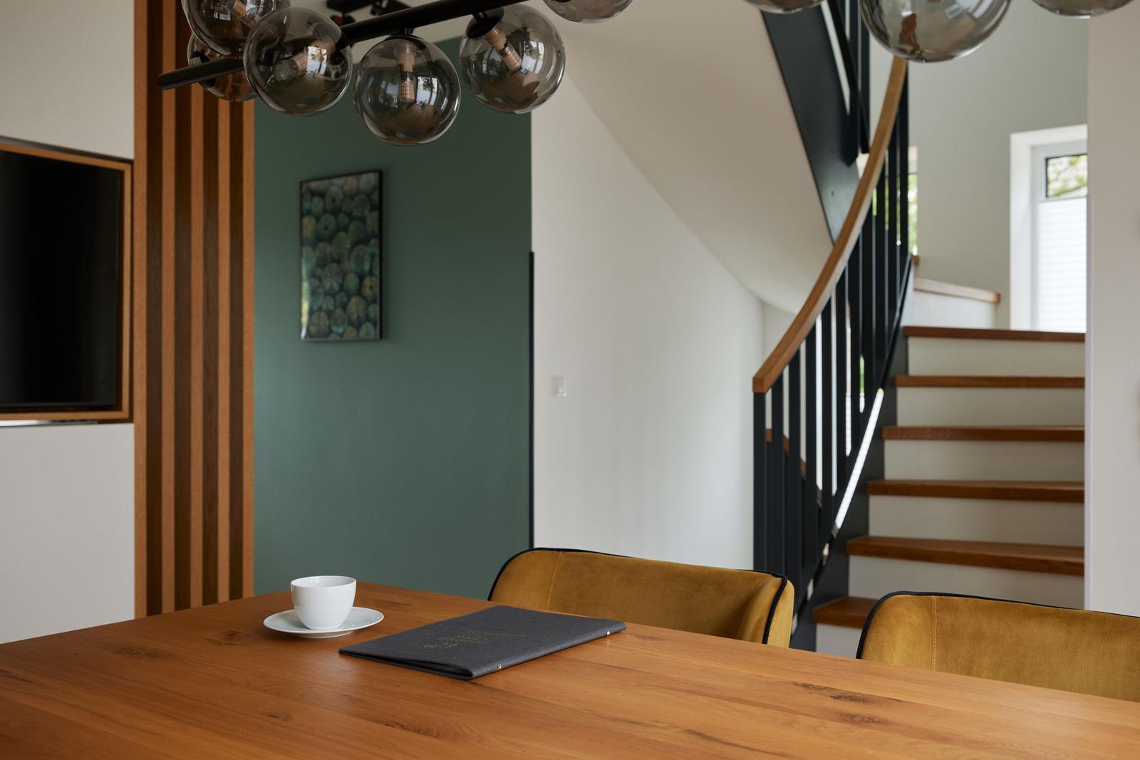 Bettkopfteil mit Kissen, Nachttisch und Lampe vor dunkelblauer Wand