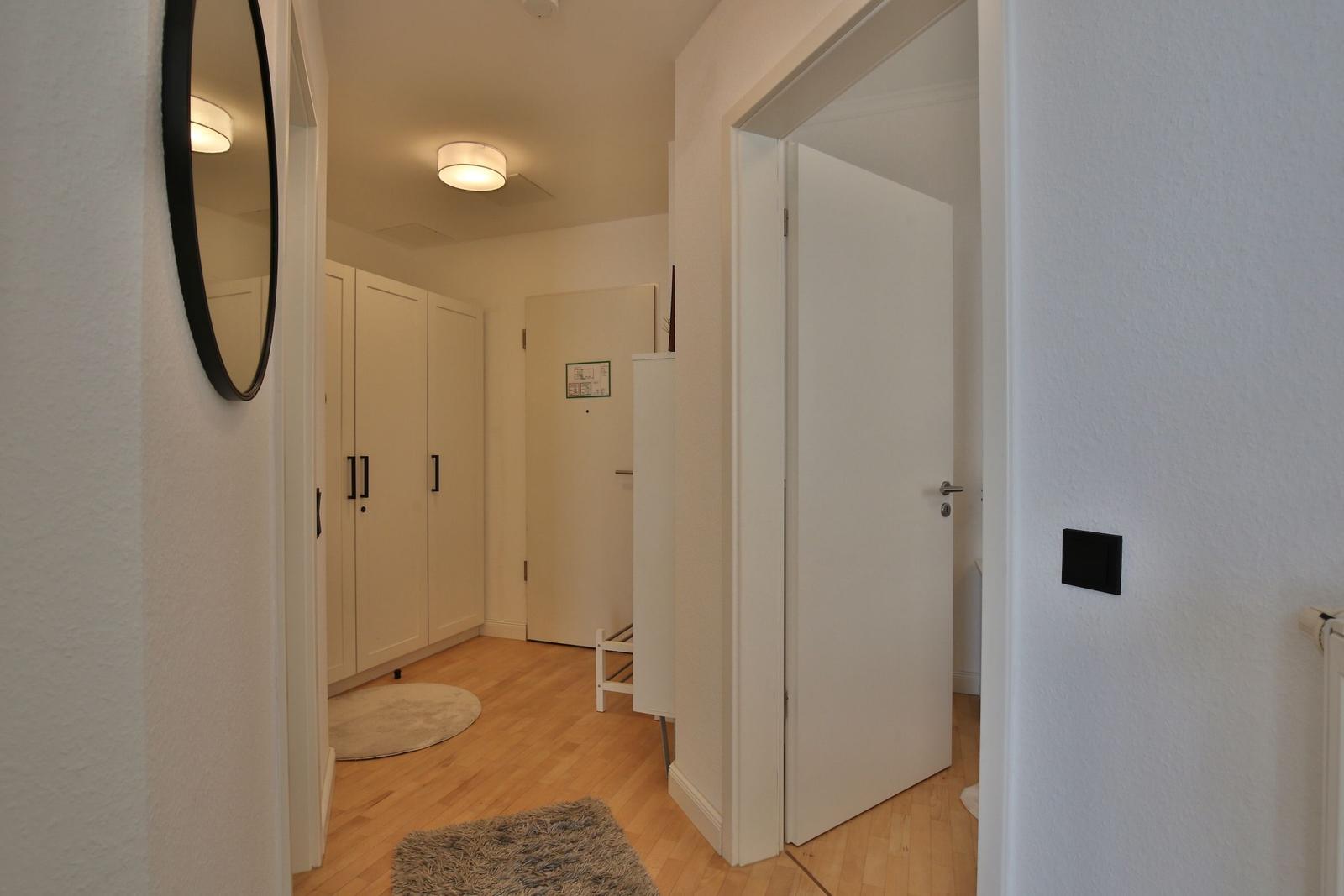 Badezimmer mit Toilette, Waschbecken und Heizkörper. Weiße Fliesen und Mosaikboden.