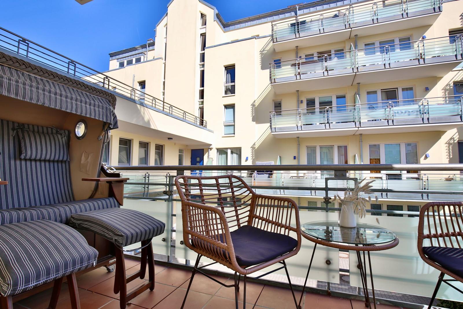 Terrasse mit zwei Stühlen und Tisch, Blick auf Gebäude mit Balkonen.