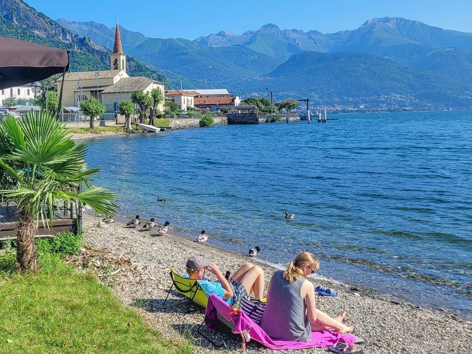 Strand mit Liegestühlen, Handtasche und Picknickkorb am Seeufer.