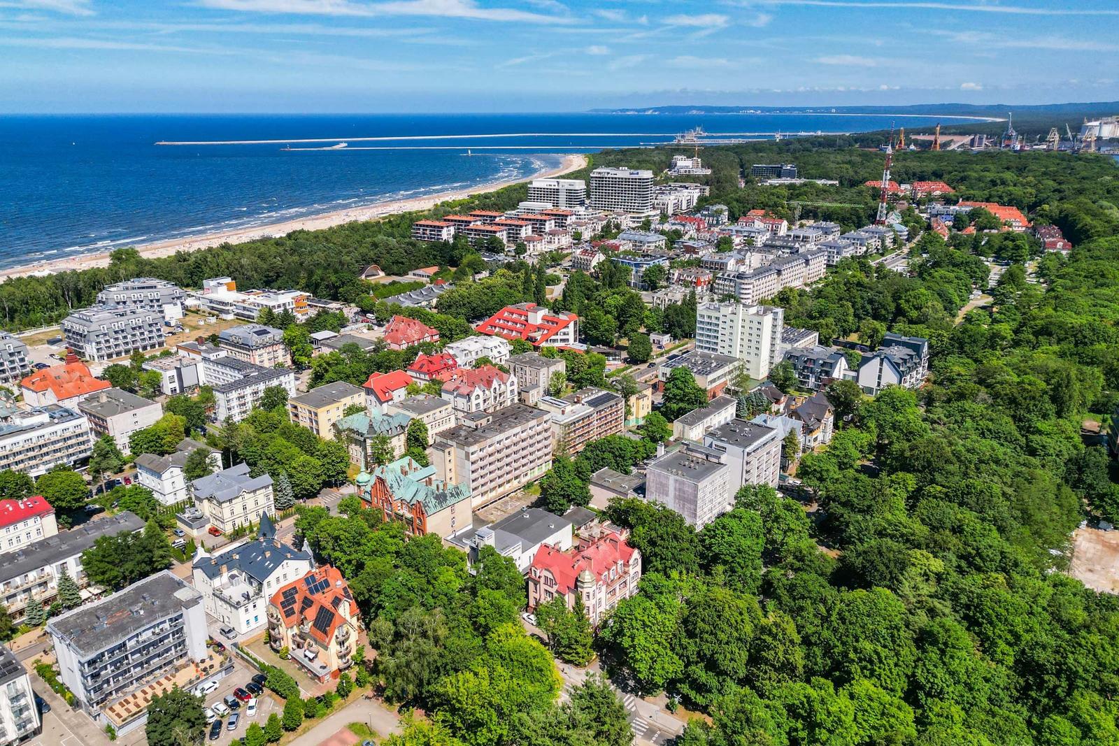 Modernes Gebäude mit Strand und Park, beleuchtete Terrassen und Gartenbereiche.