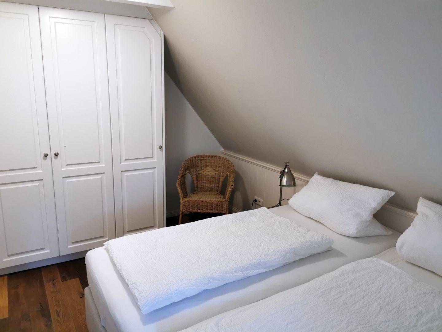 Schlafzimmer mit Dachschrägen, Bett, Fenster und Fernseher.
