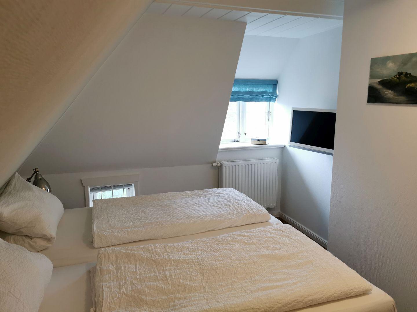 Zwei Betten in einem Dachzimmer mit Holzboden und Wandbild.