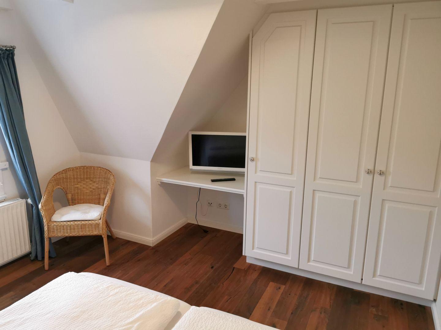 Zwei Betten in einem Dachzimmer mit Holzboden und Bildern an der Wand.