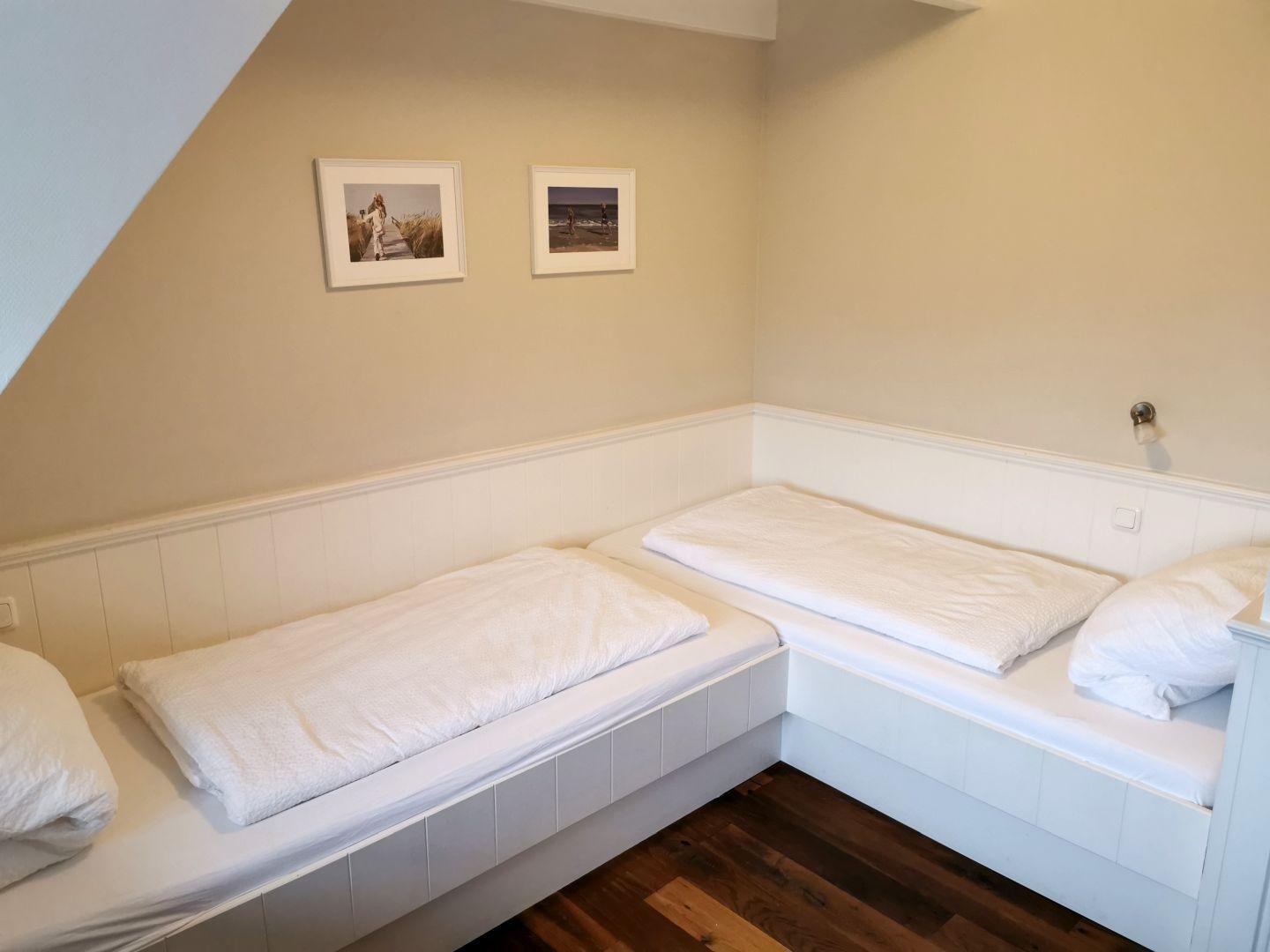 Schlafzimmer mit rotem Schrank, Holzboden und Fenster mit blauen Vorhängen.