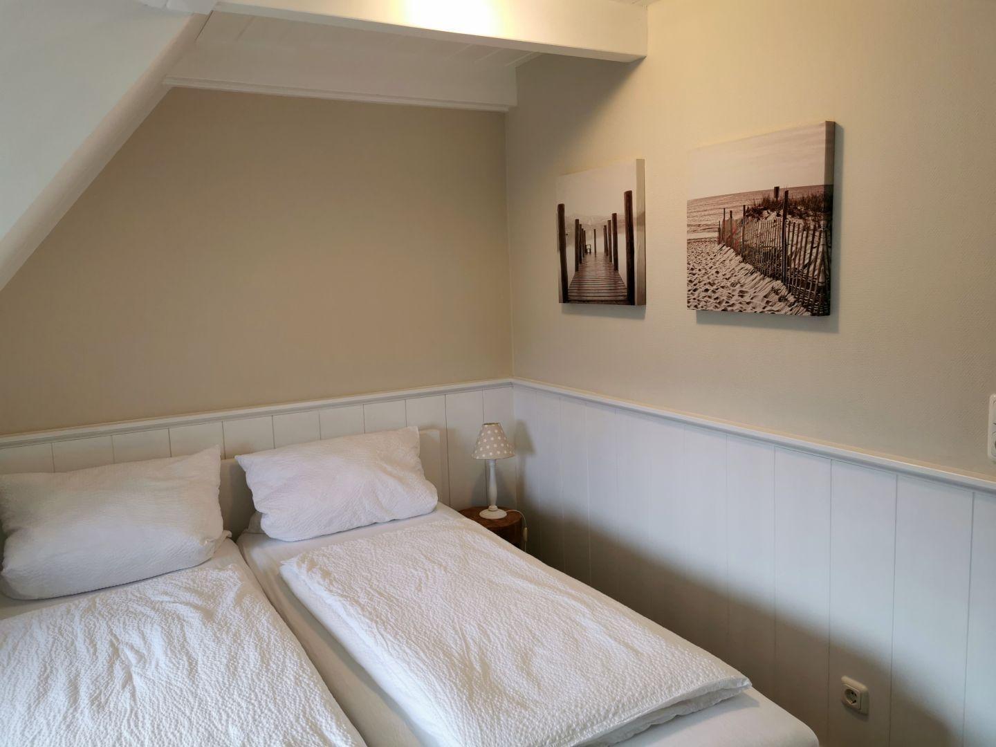 Schlafzimmer mit Einzelbett, Fenster und Wandbild.