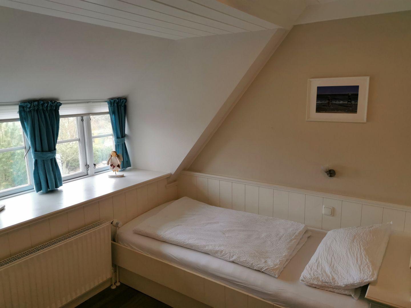Schlafzimmer mit Bett, Kleiderschrank und Wandbild.