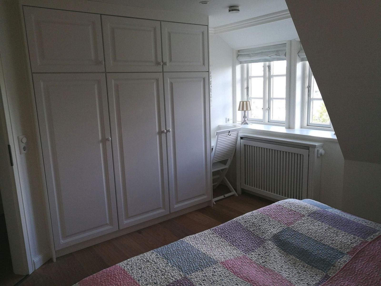 Zwei Betten mit rosa Bettwäsche und Kissen in einem Zimmer mit Holzboden und Fenster.