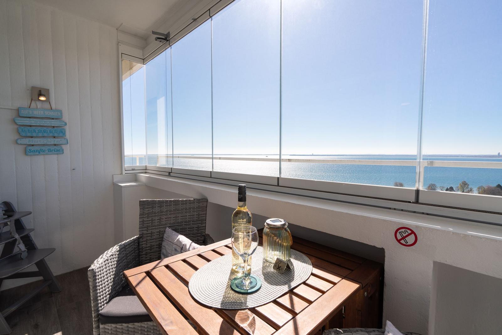 Terrasse mit Tisch und Sitzgelegenheiten. Blick auf See und grüne Landschaft.