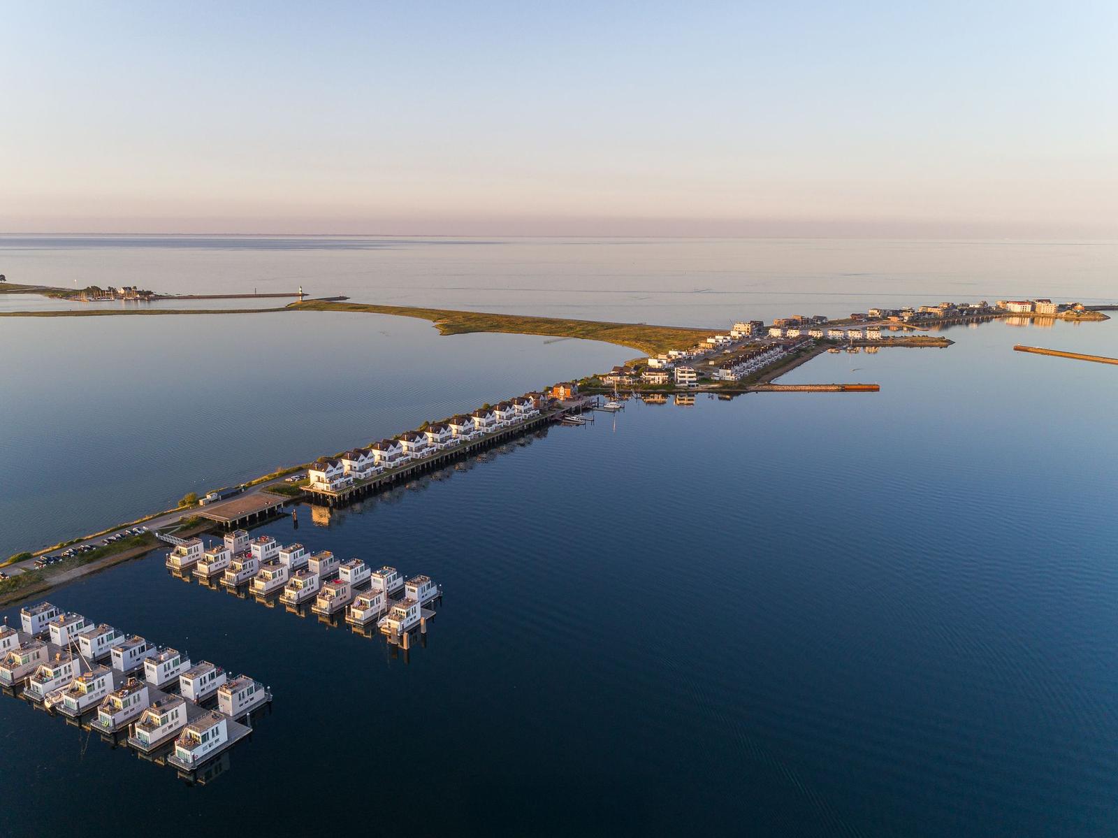 Aerielansicht eines Hafens mit Booten und Wohnhäusern am Wasser.