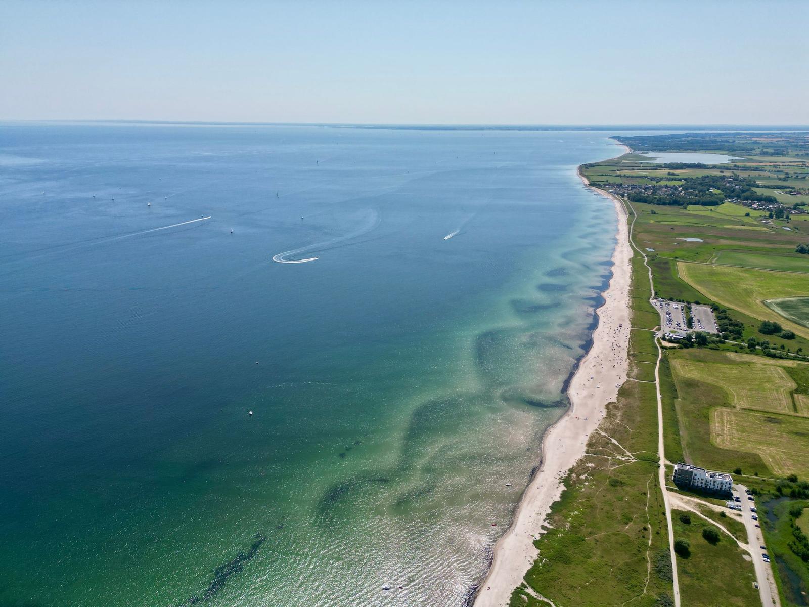 Aerielansicht eines Hafens mit Yachten und Wohngebieten an der Küste.
