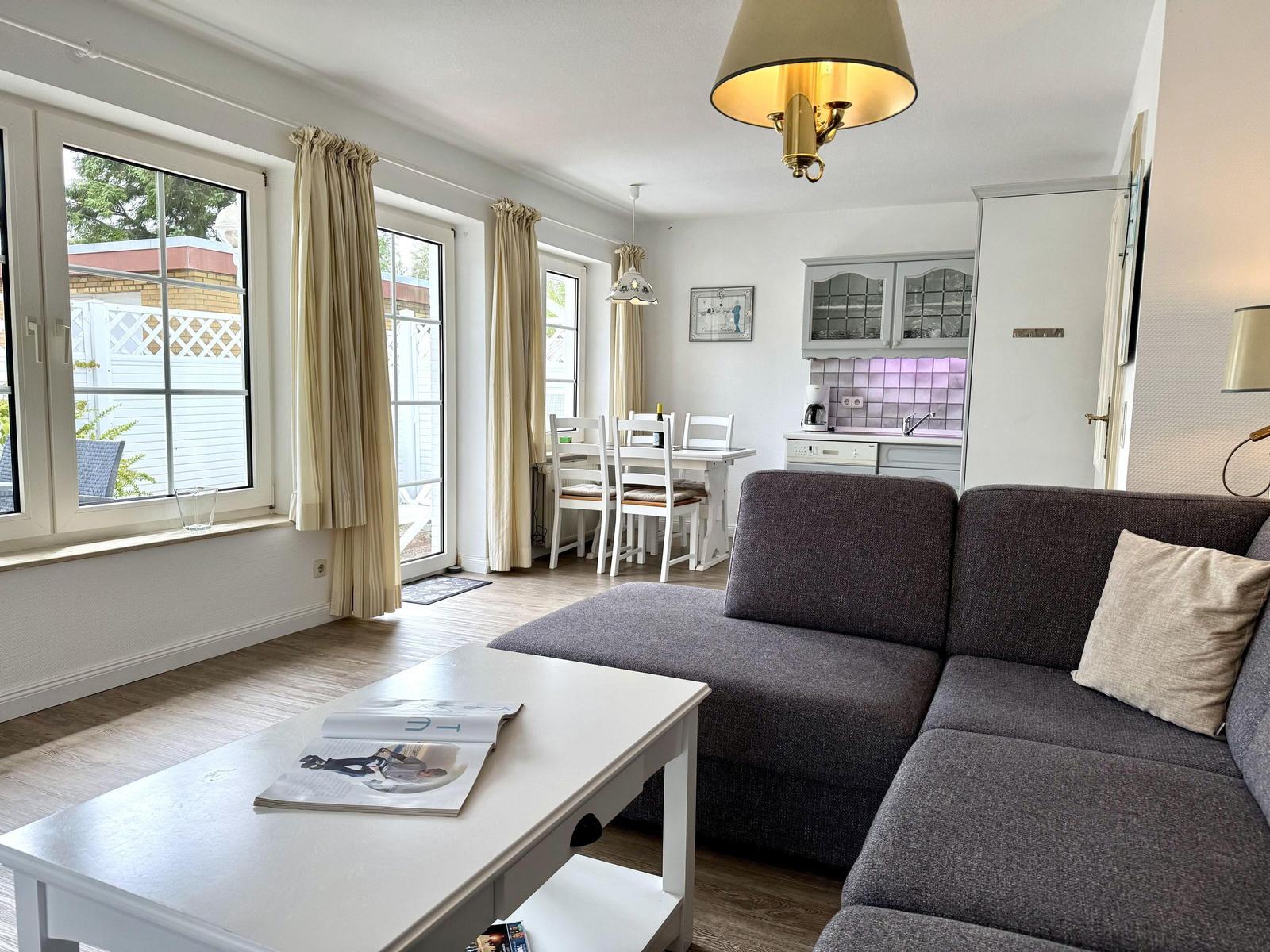 Living dining area with corner sofa, dining table, pendant lights and kitchen.
