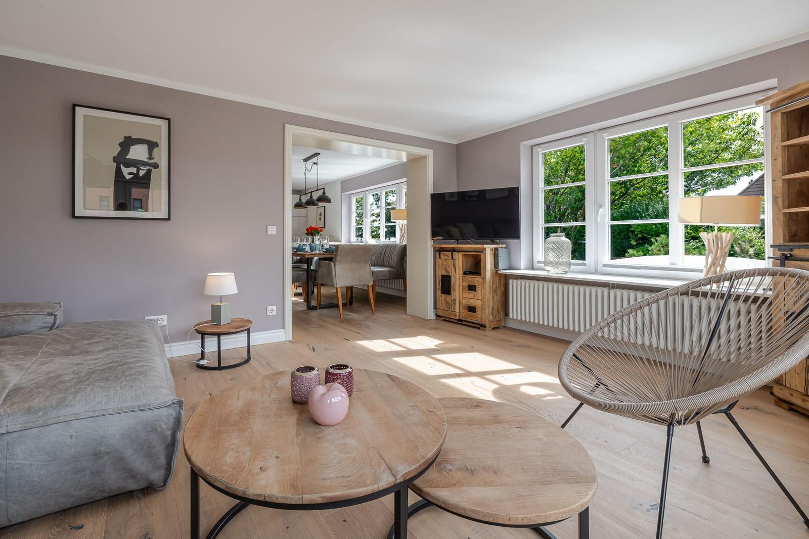 Wohnzimmer mit Sofa, Rundsessel und Blick ins Esszimmer mit Holztisch.