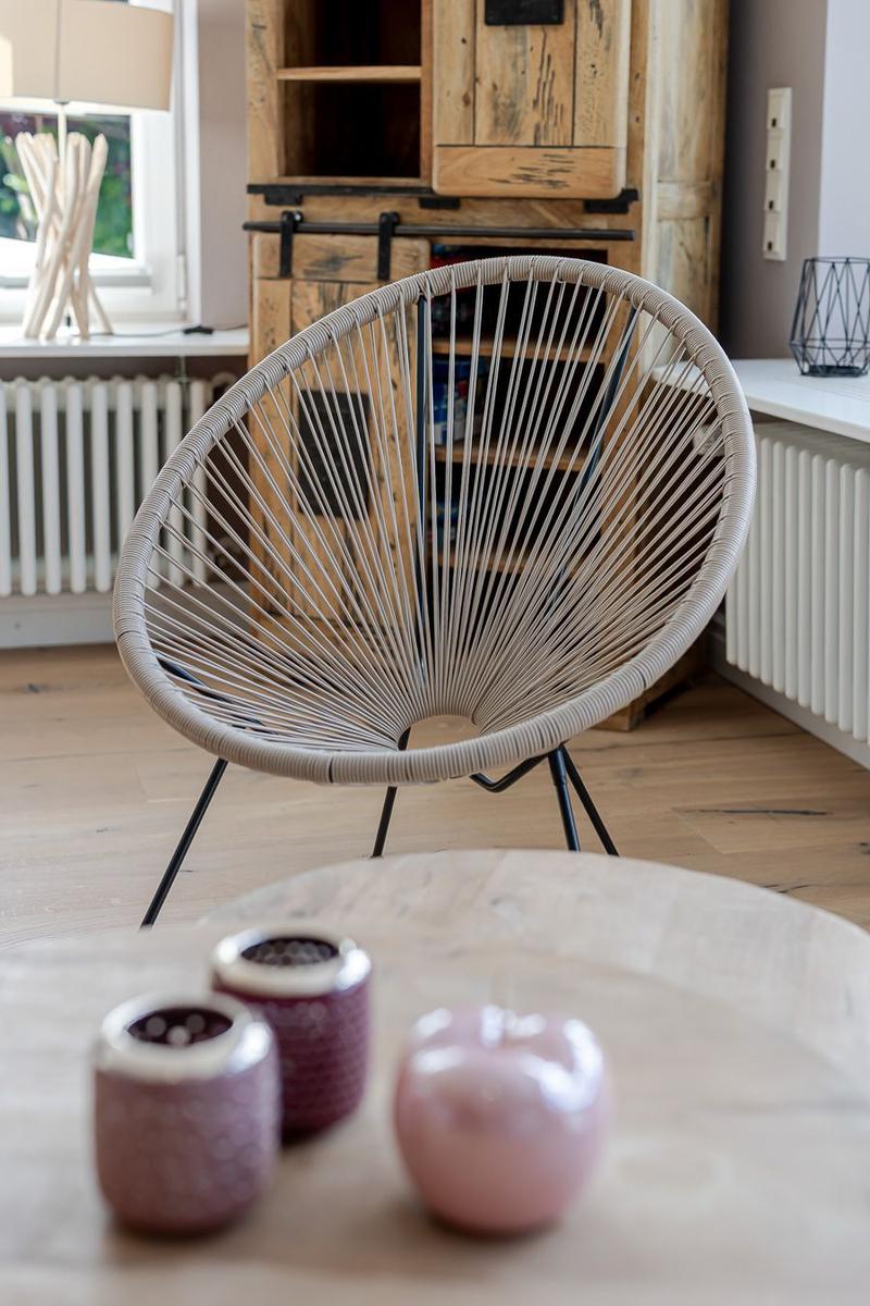 Runder Schnursessel vor Holzschrank, Fenster mit Lampe und hellem Holzboden.