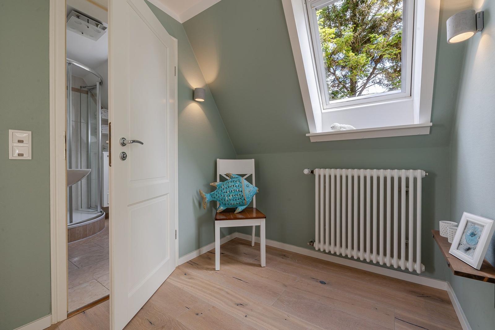 Zimmer mit grünen Wänden, Dachfenster, Fischkissen und Blick ins Bad.