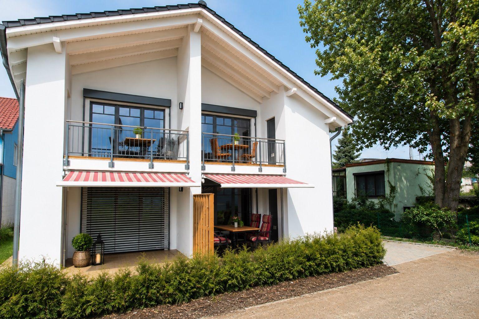 Moderne weiße Villa mit Balkon und Terrasse. Holzgitter und Garten.