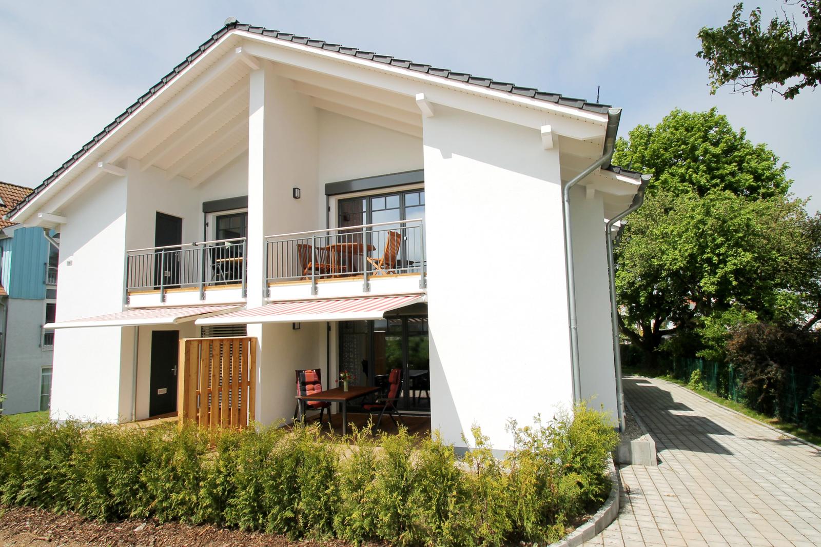 Moderne Villa mit Balkon, Terrasse und Garten. Garagenbereich und große Fenster.