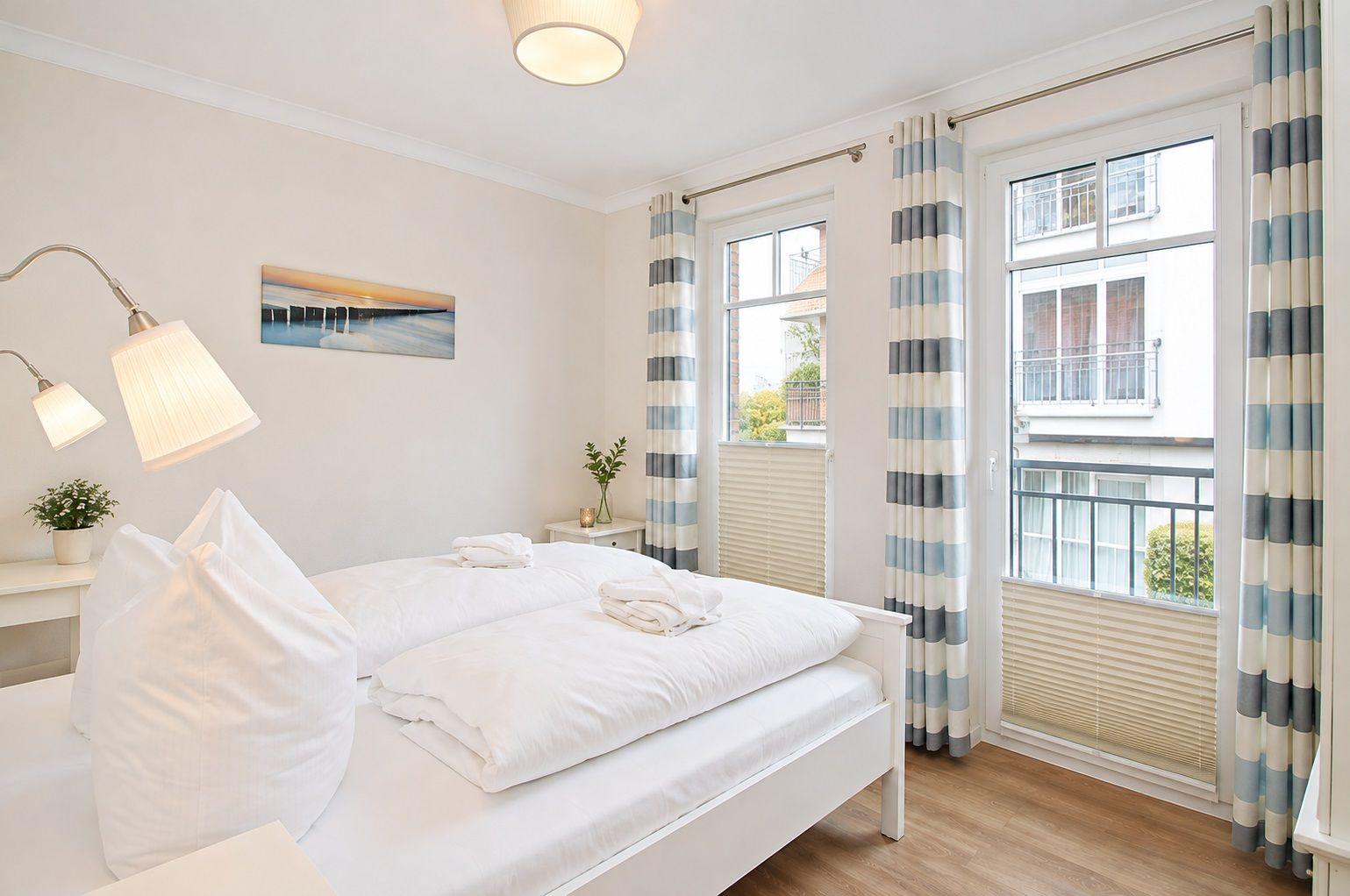 Schlafzimmer mit Bett, Fenster und Gardinen.