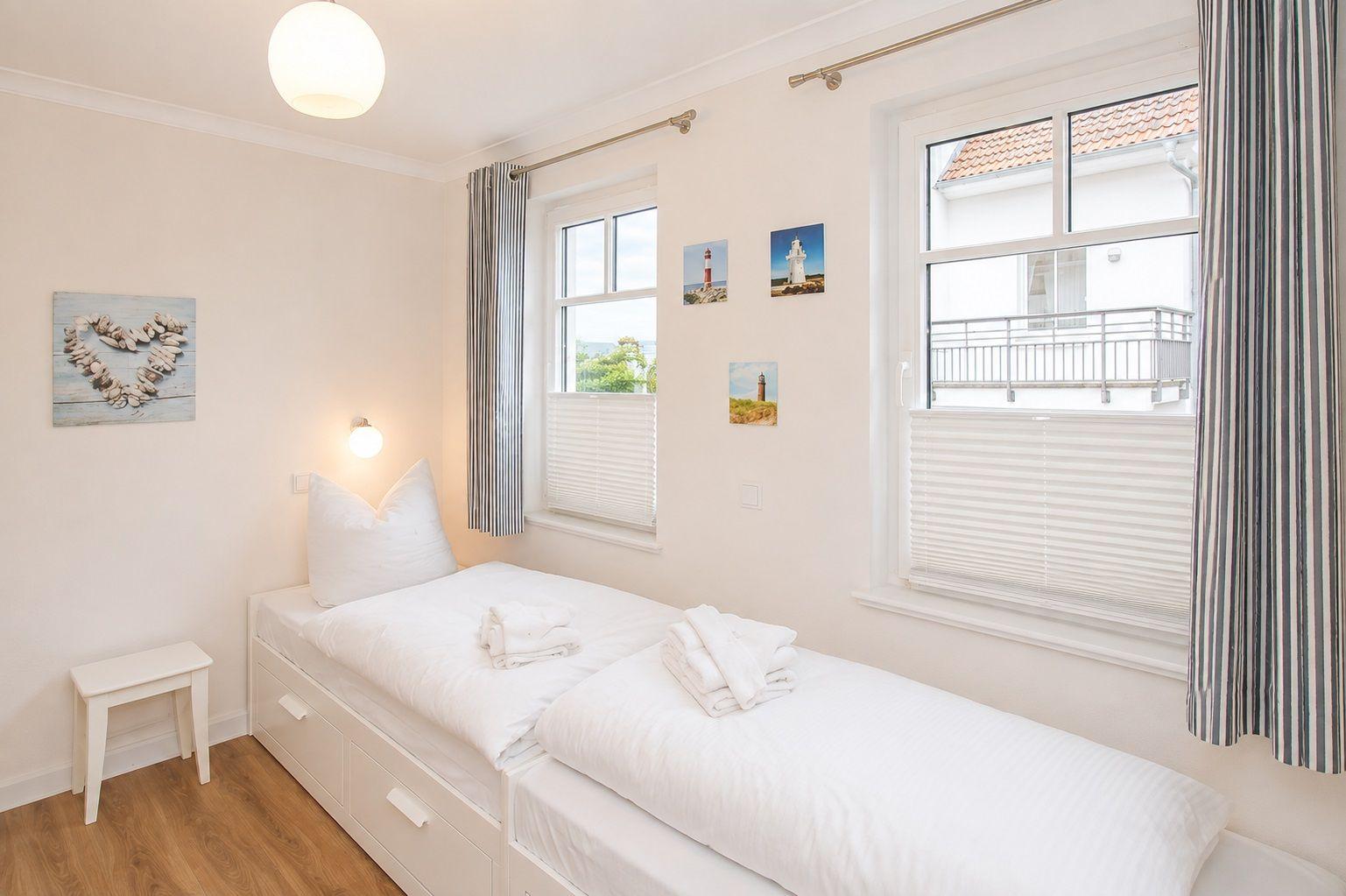Schlafzimmer mit Doppelbett, Fenstern und Wandbildern