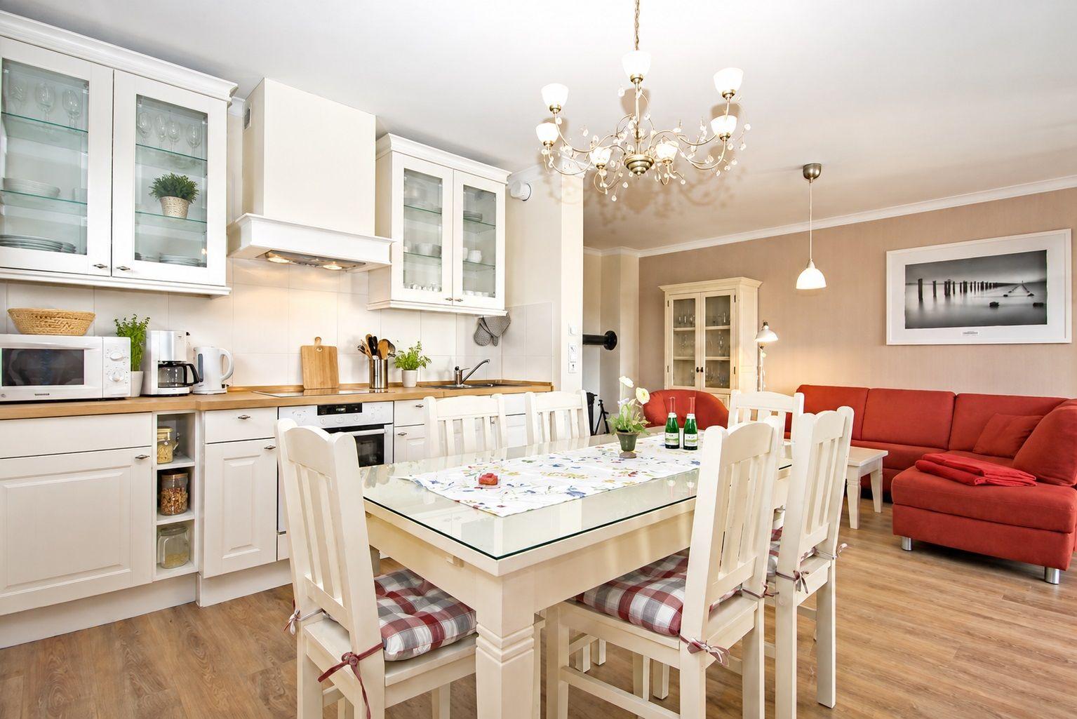 Küche mit Essbereich und Wohnzimmer mit rotem Sofa und Kronleuchter.