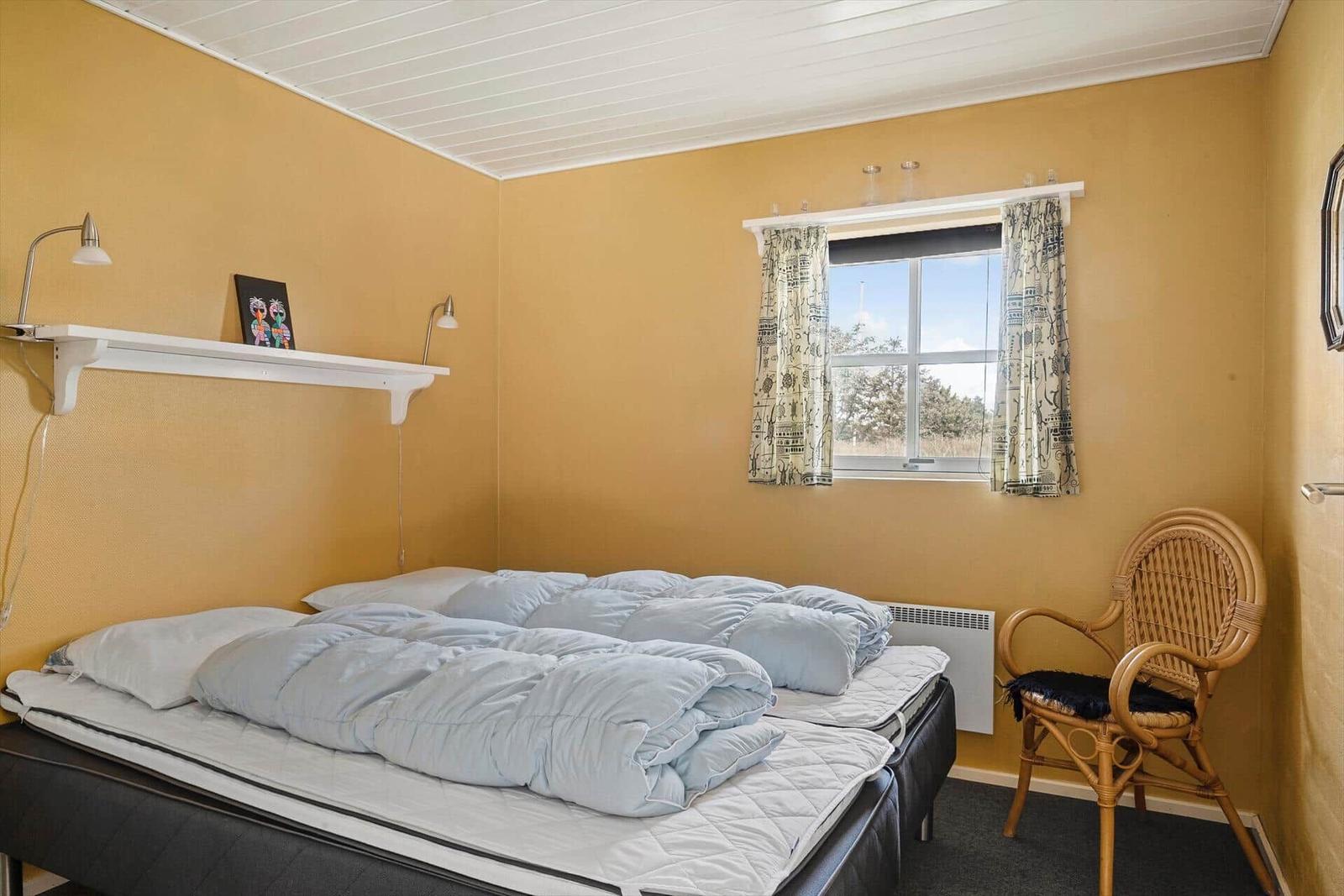 Schlafzimmer mit Bett, Schrank und Stuhl. Durchgang zur Küche.