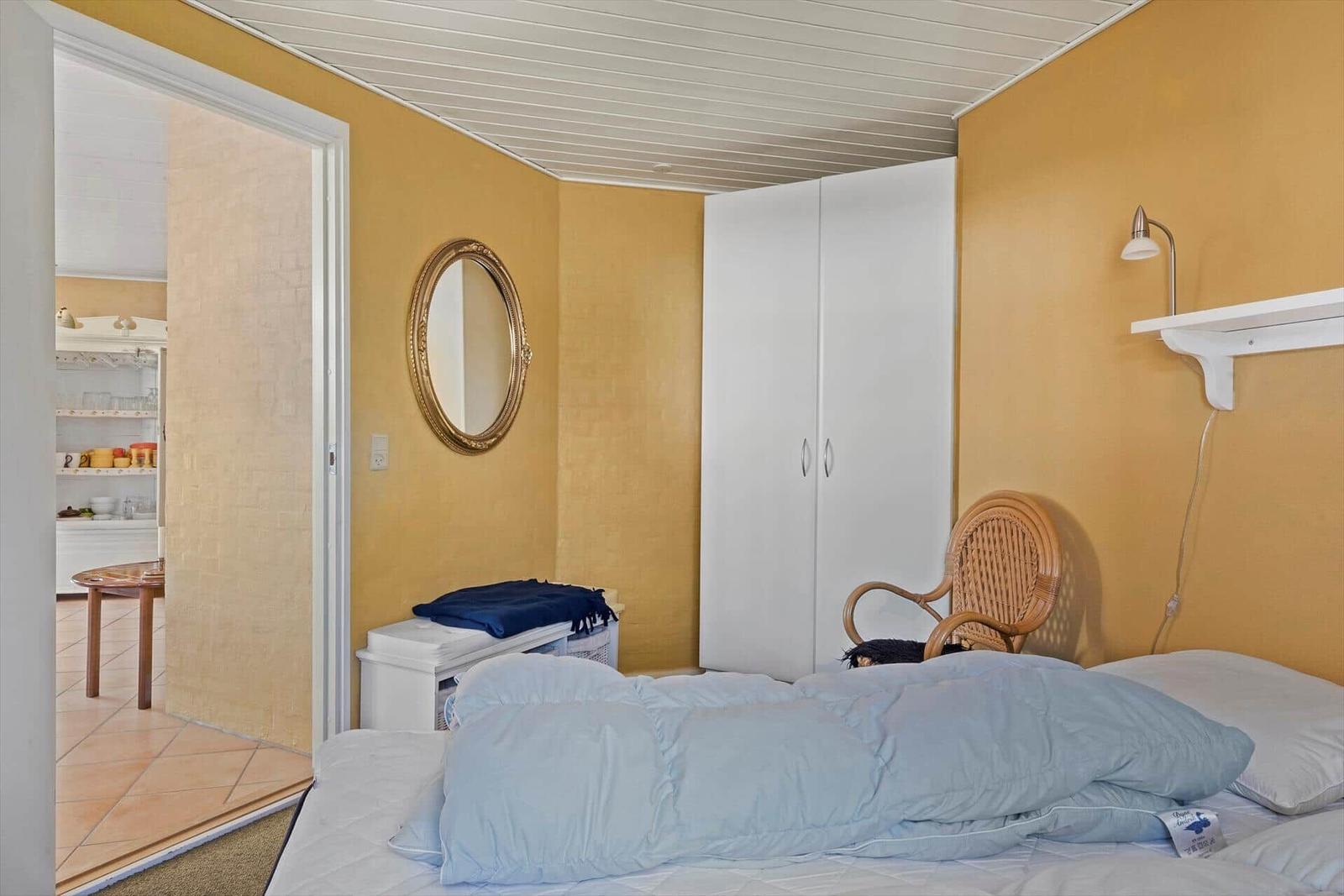 Schlafzimmer mit Bett, Stuhl und Fenster mit Vorhängen.