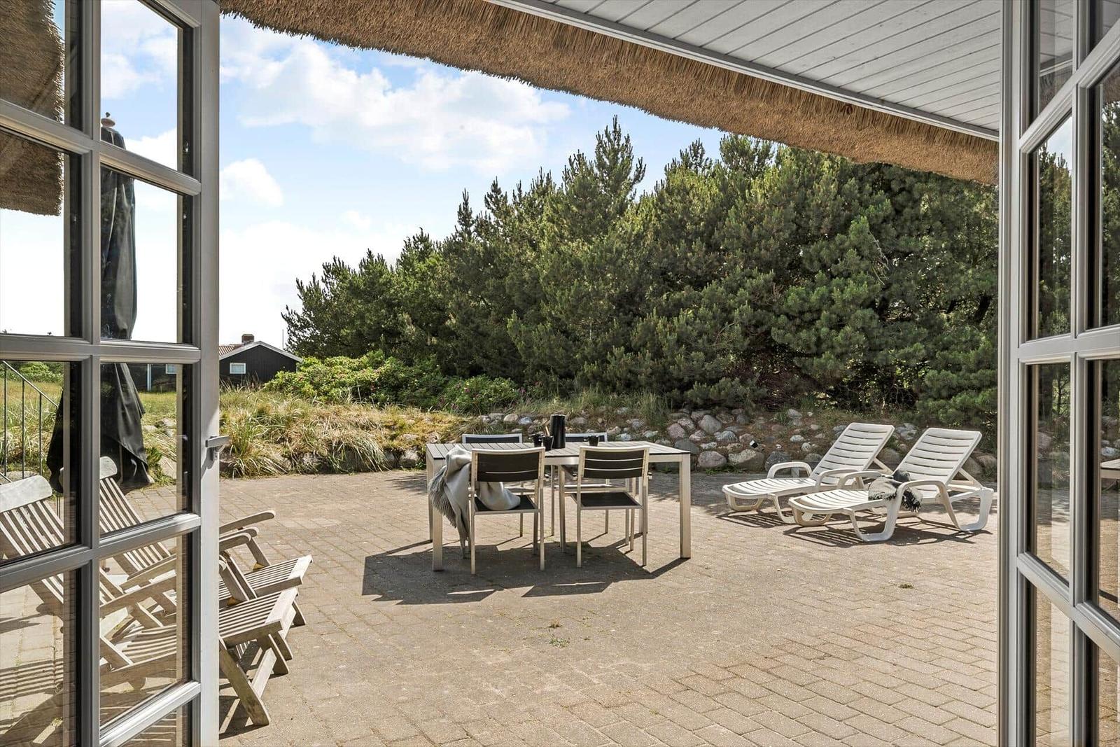 Holzhütte mit Strohdach und Terrasse im Grasland.