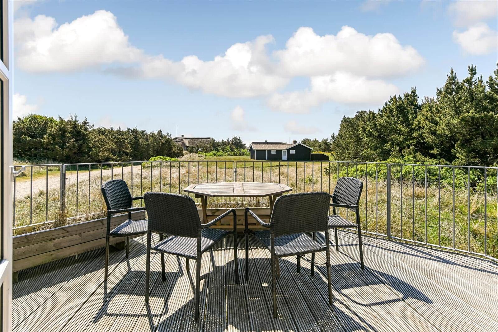 Haus mit Strohdach, Terrasse und Gartenbereich mit Liegestühlen und Tisch.