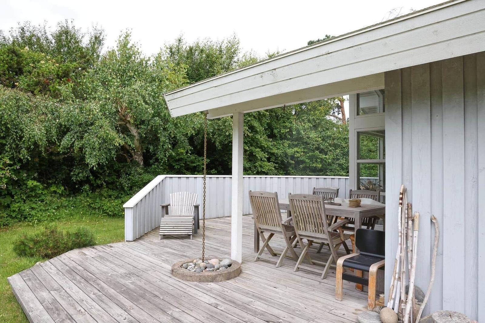 Holzterrasse mit Korb voller Steine und getrockneten Zweigen an der Wand