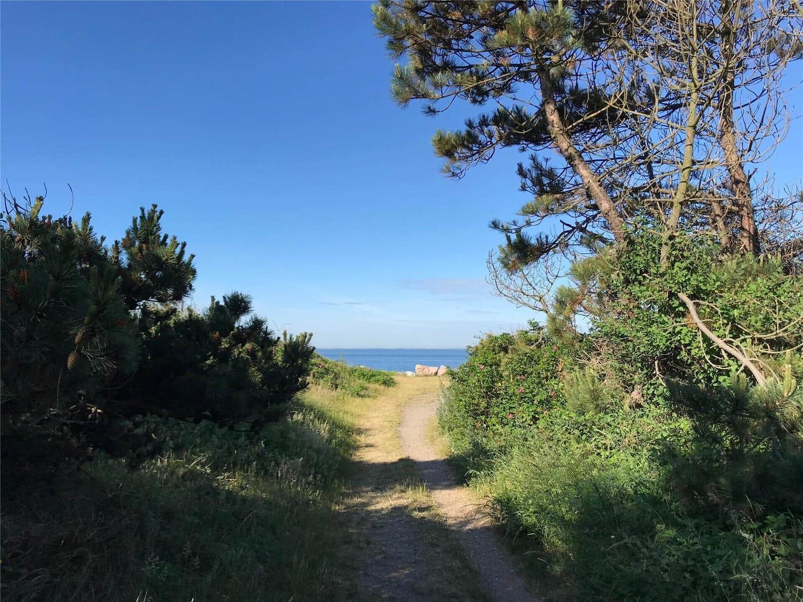 Füße am Strand mit Blick auf das Meer und Felsen.