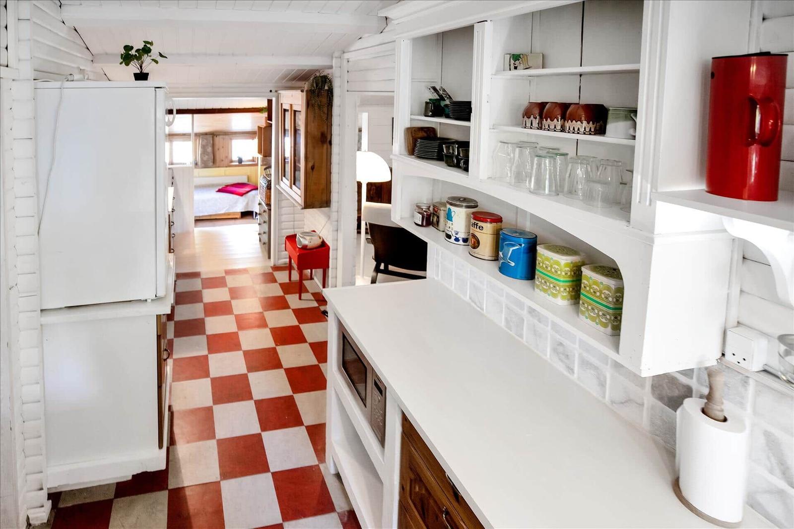 Schlafzimmer mit Bett, Holzdecke, Wandbild und Schrank. Blick in angrenzenden Raum.