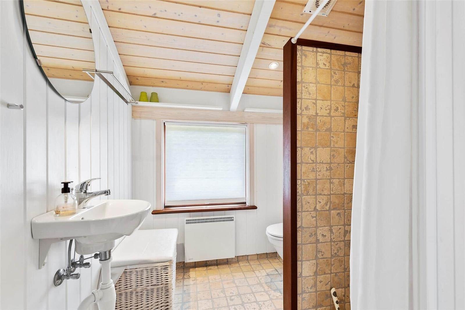 Großes Wohn- und Esszimmer mit Kücheninsel und Meerblick durch große Fenster.