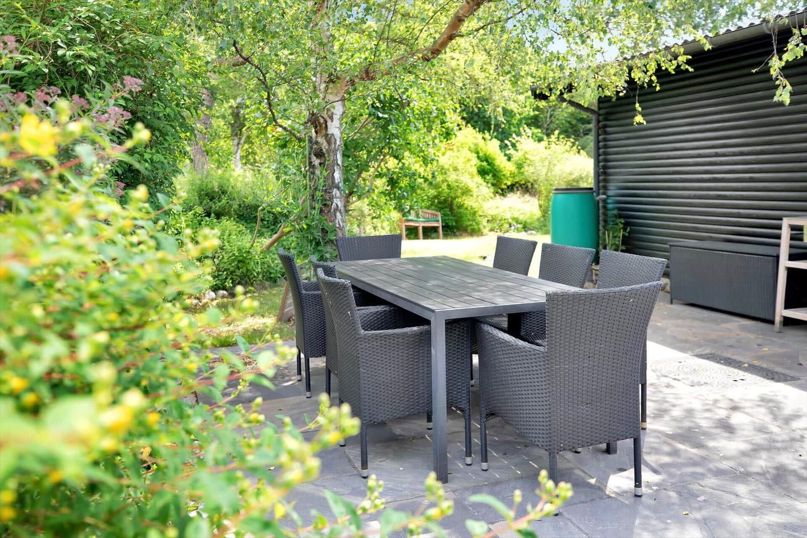Schwarzes Holzhaus mit Terrasse, Garten und Grillplatz.