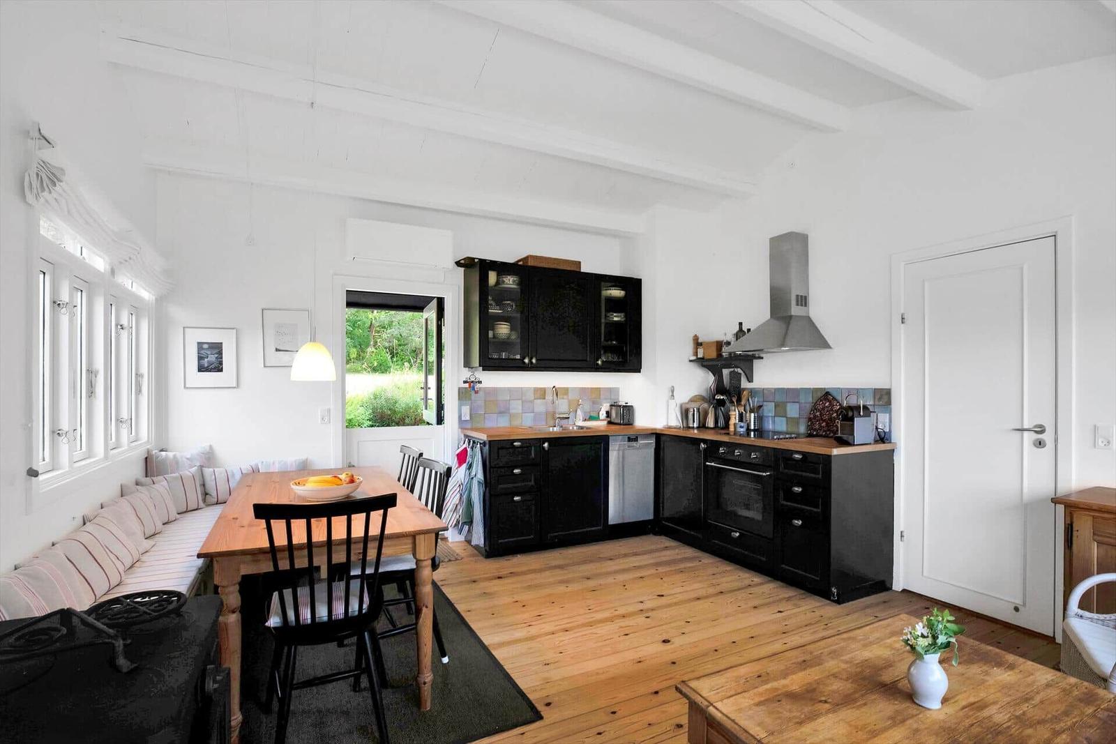 Schlafzimmer mit Bett, Holzschrank und Fenster mit Blick auf Bäume.