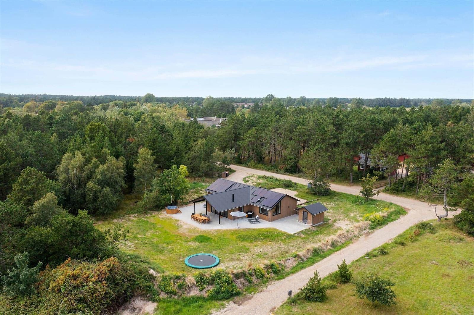 Moderne Holzhütte mit Pool, Grill und Terrasse im Wald.