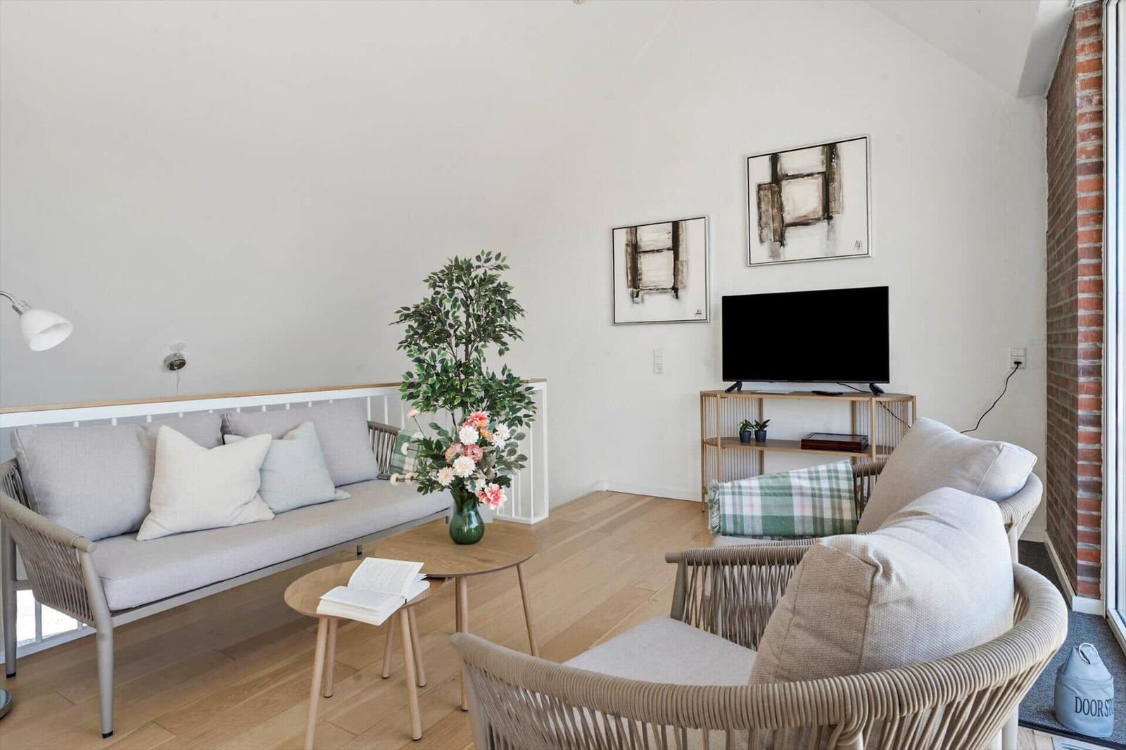 Schlafzimmer mit Balkon, Bett, Sofa und Tisch mit Blumen.