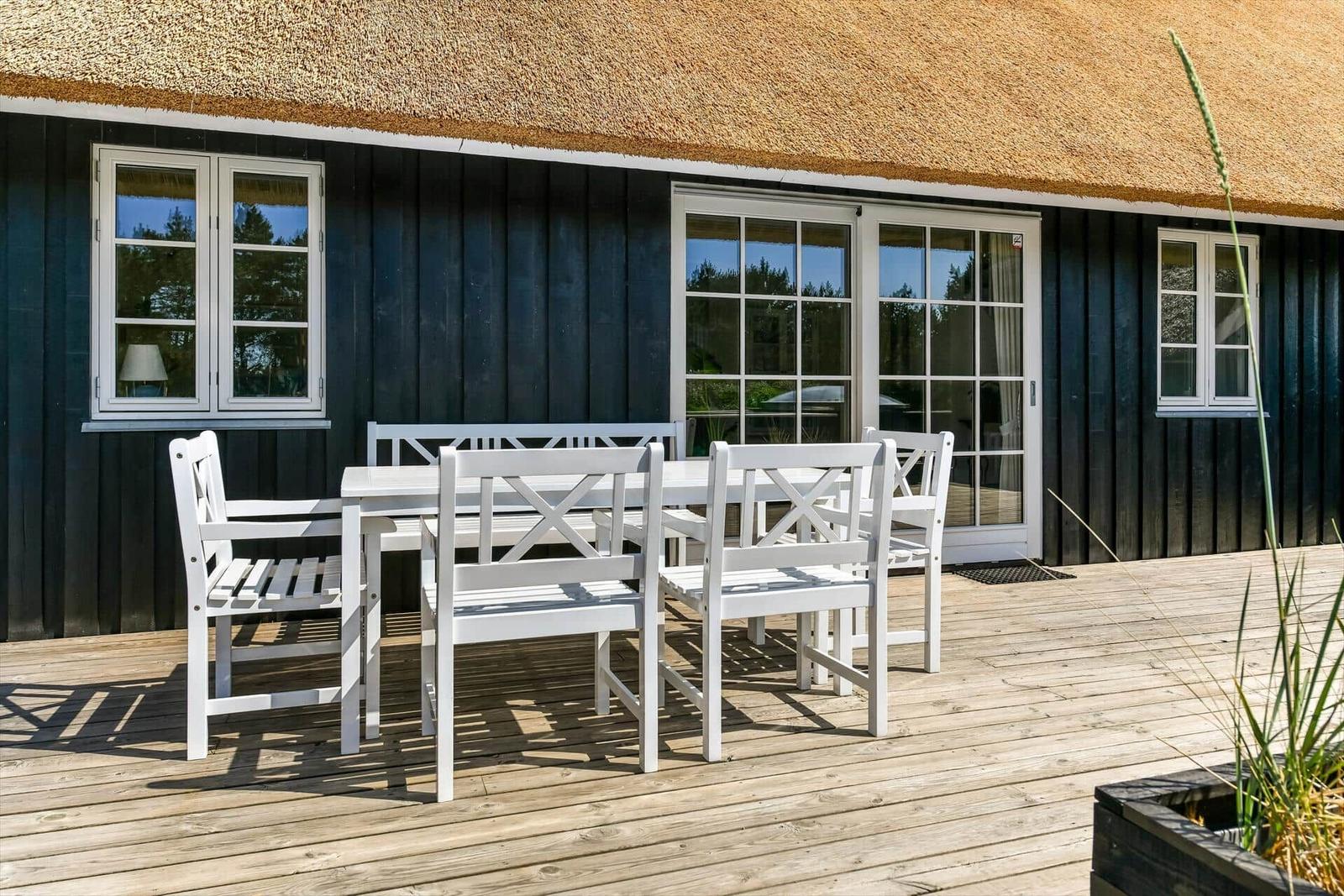 Haus mit Strohdach und Spielplatz mit Schaukel im Vorgarten.
