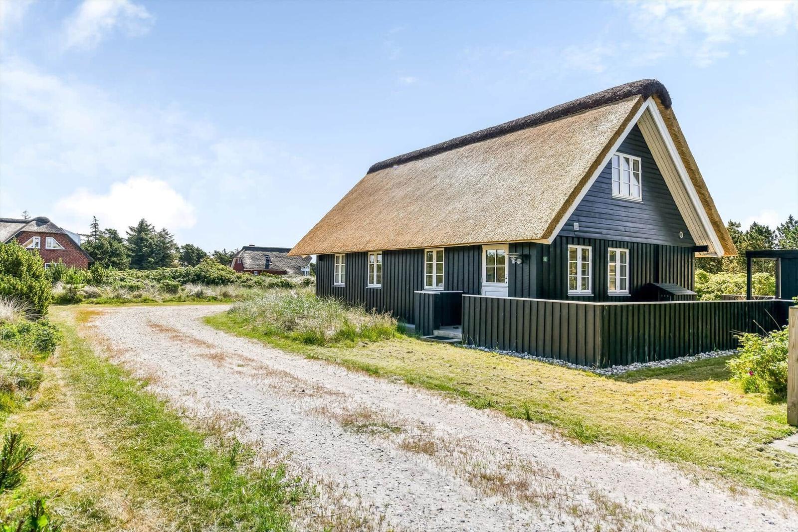 Eingangstür mit Schild BANGSBO an schwarzem Holzhaus mit Holzveranda.