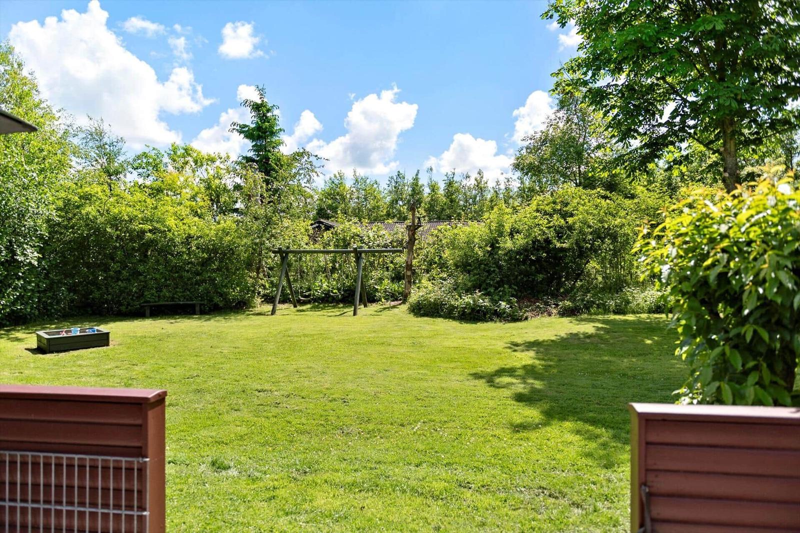 Ein Spielplatz mit Sandkasten und Schaukel im Garten.