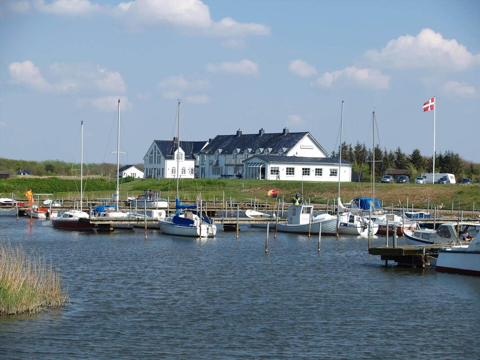 Hafen mit Booten und Steg, Blick auf das Meer und grüne Uferbereiche.